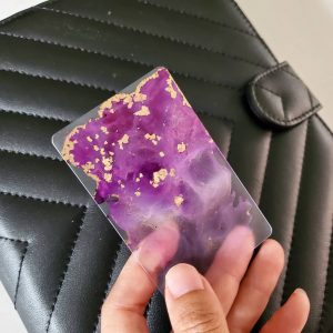hand holding a purple alcohol ink painted planner card in front of an agenda cover